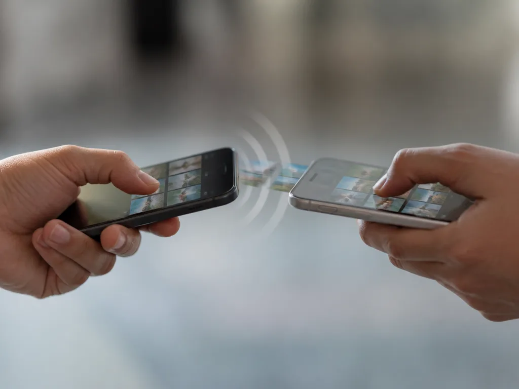 Två personer håller sina mobiltelefoner nära varandra för att dela en fil trådlöst